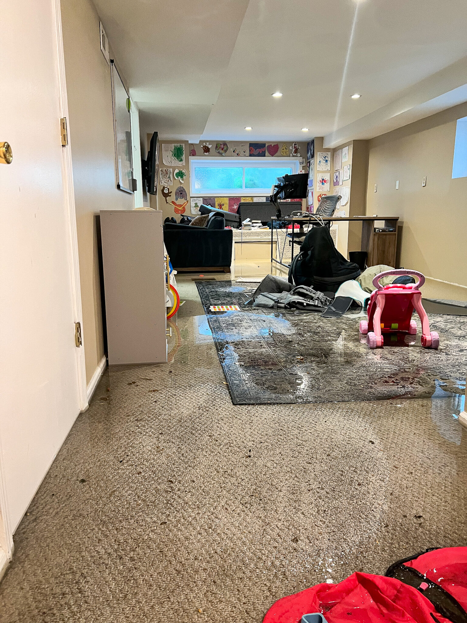 Basement after flood damage — soaked carpet, sewage, displaced furniture